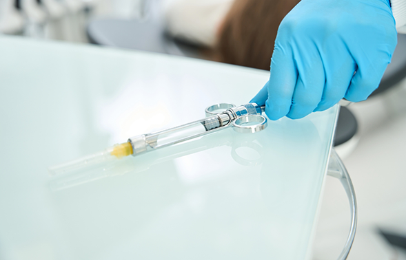Dental professional grabbing a syringe