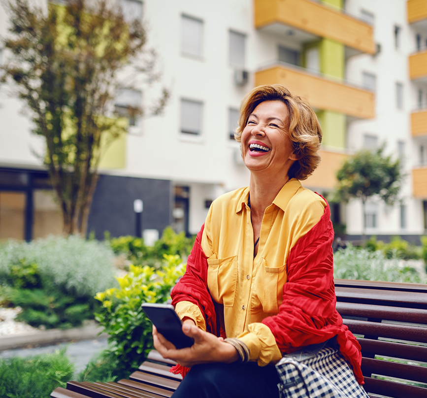 Woman laughing on a park bench after getting dental implants in Prosper
