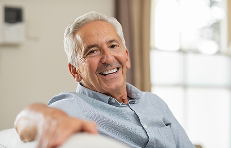 Smiling older man sitting on a couch with his arm over the back