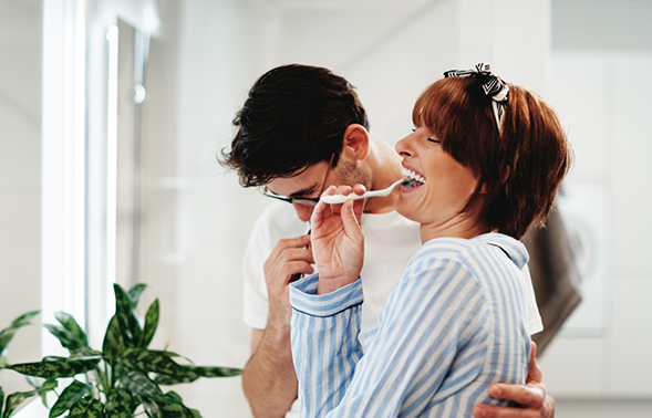 Man and woman brushing their teeth together