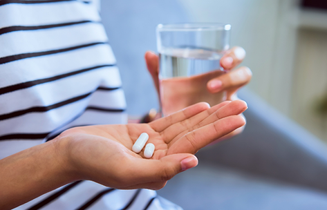 Person taking two pills with a glass of water