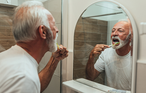 Senior man brushing his teeth at home