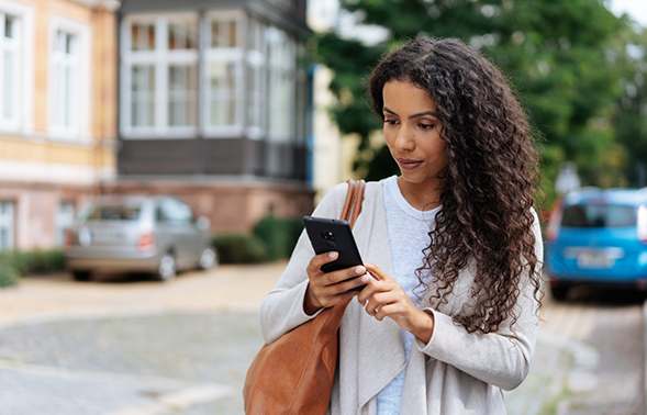 Woman standing outdoors and looking at her phone