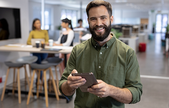 Smiling man holding a tablet in an office