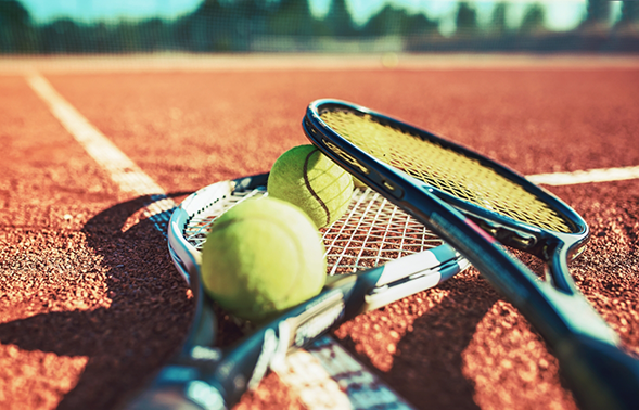 Two tennis balls and rackets on a tennis court