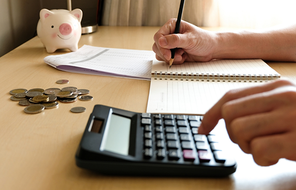 Person typing on a calculator and writing in a notebook