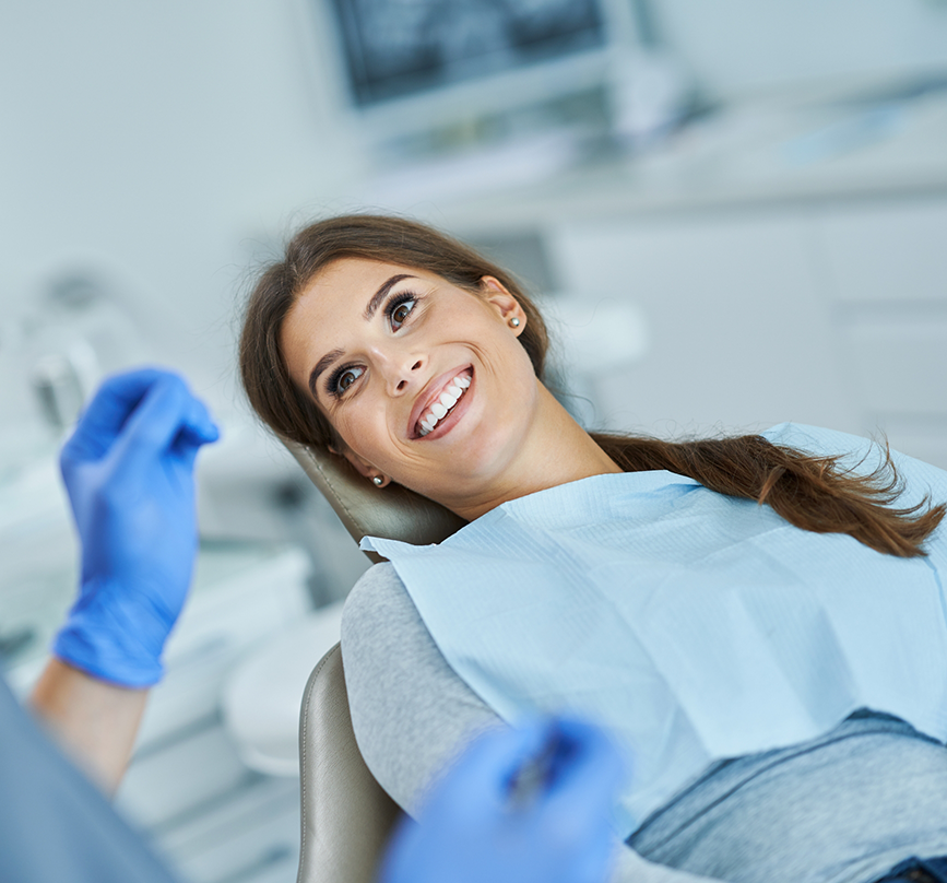 Smiling woman in the treatment chair listening to her oral surgeon in Prosper