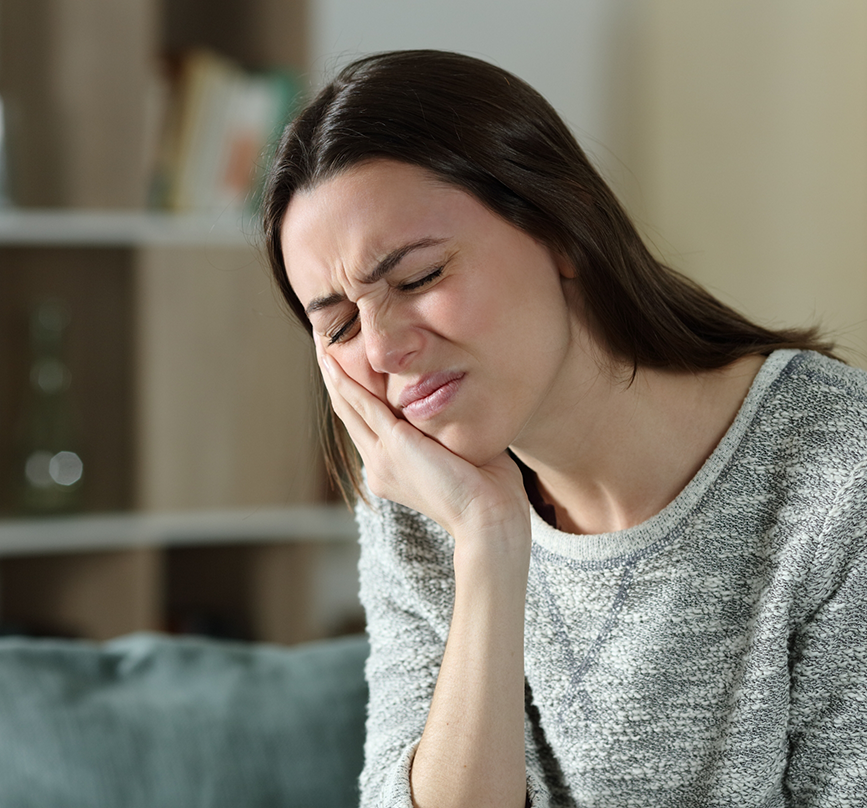 Woman holding the side of her jaw in pain before TMJ treatment in Prosper