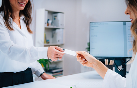 Woman handing her payment card to a front desk team member