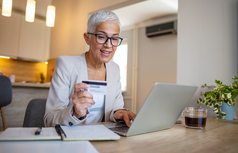 Woman entering her payment card information into a laptop