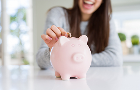 Woman putting a coin into a piggy bank